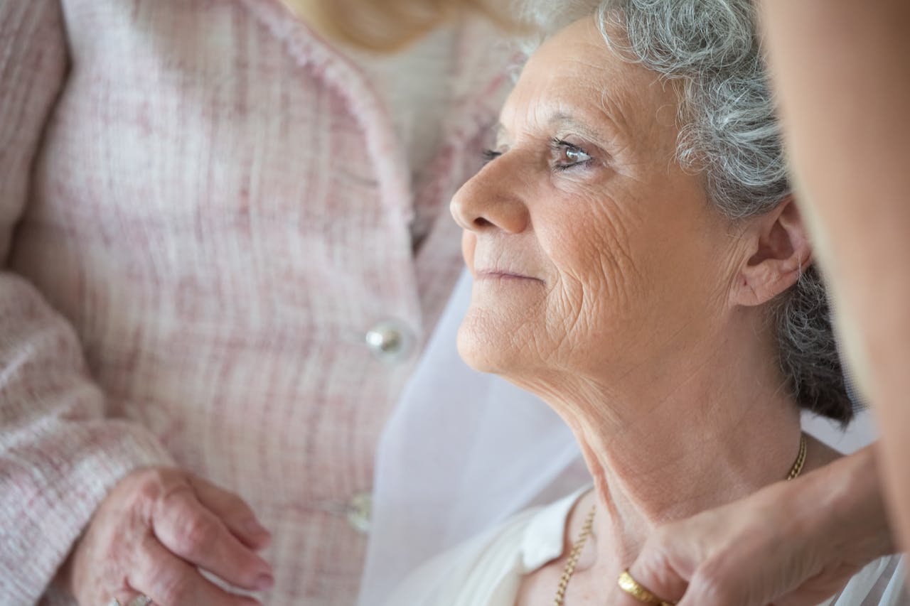 Close-up of a serene elderly woman with gray hair in a peaceful indoor setting.